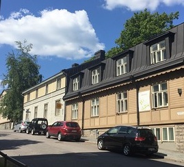 Helsinki street scene with row houses and cars parked at the curb. Photo by John Lloyd. Licensed CC BY 2.0 DEED.